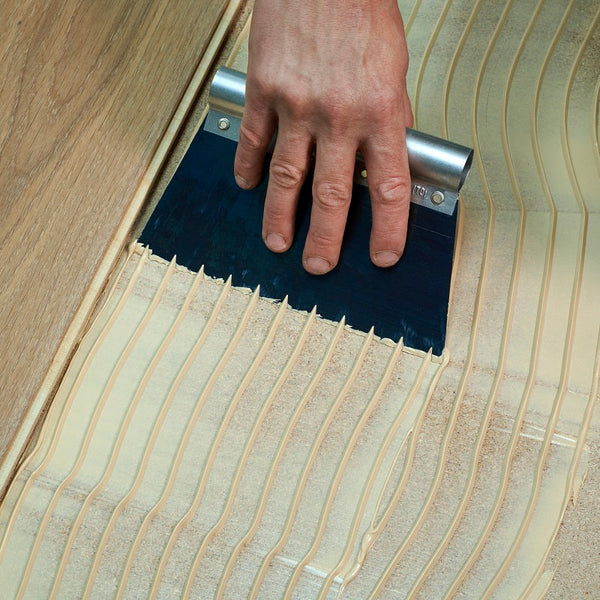 Person applying adhesive to a floor